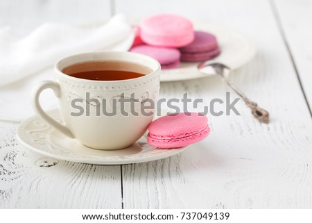 Macaroons with hot tea on wooden table.