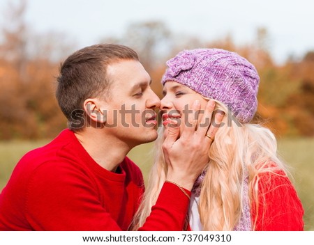 Beautiful young couple, man and blonde hair woman, enjoy autumn. They clothed red fashion sweater.  Family nature portrait. Happy people. Close up. 