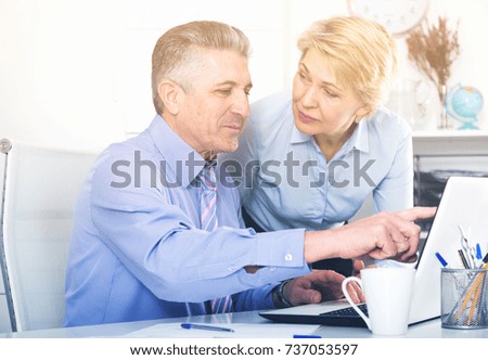 Mature man and woman watch interesting information on internet at ofice