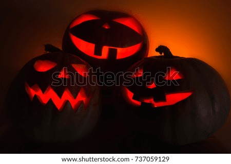 Scary Halloween pumpkins. Halloween card concept. Spooky glowing faces. Photo of three pumpkins of Halloween on a wooden table