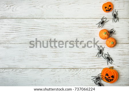 Halloween vintage background with cookies and spiders, top view. Halloween decorations on white texture wood planks with space. Sweet pumpkins on wooden rustic table for Hallowen. Flat lay photo.