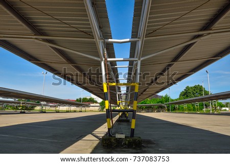 Perspective view of empty outdoor parking lot and metal sheet roof, metal structure with shadow and blue sky background