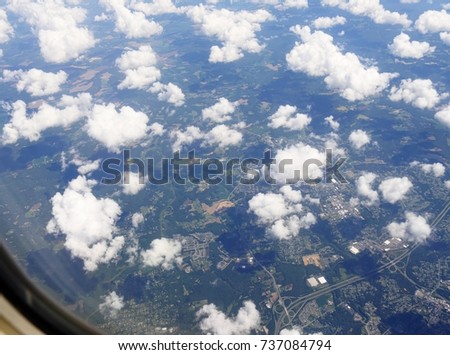 Aerial view above Atlanta, Georgia with fluffy white clouds seen from an airplane window