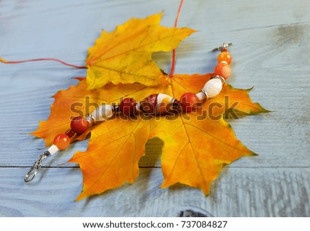 Bracelet made of Murano glass and carnelian on a background of autumn leaves on a blue wooden table.