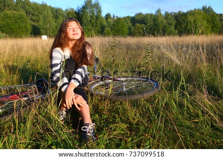 teenager girl sit with  bicycle on the country field road sunny summer photo