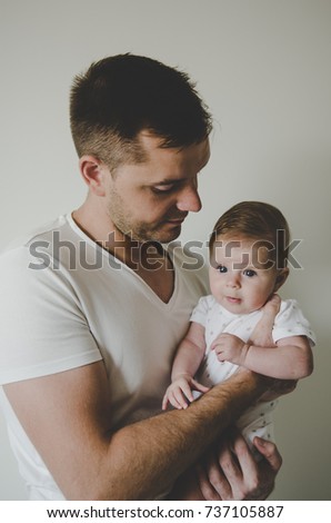 Young handsome father holding her little baby girl in hands and looking with tenderness on white background 