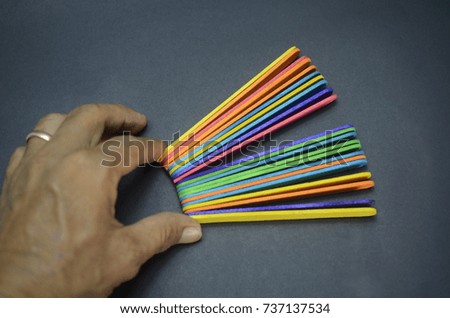 hand holding a colorful wooden sticks on black background