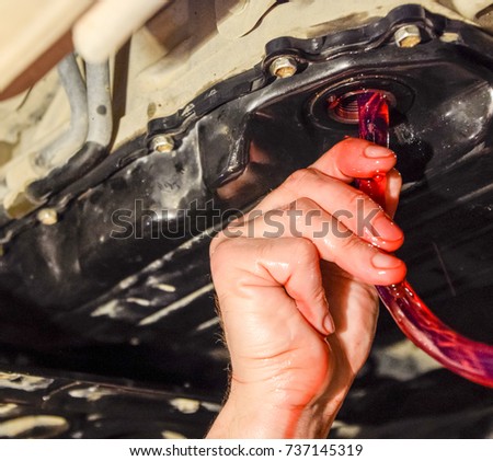 Oil change in automatic transmission. Filling the oil through the hose. Car maintenance station. Red gear oil. The hands of the car mechanic in oil.