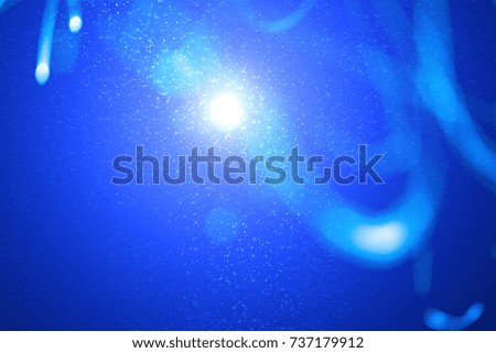 Abstract xmas blue magic sparkles or glitter lights. Christmas festive dark background. Defocused lines bokeh or particles. Template for design