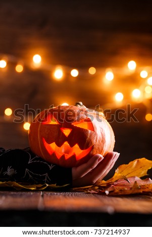 Picture of halloween background with pumpkin and witch hand on wooden table against grunge bokeh lights background