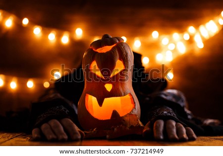 Photo of halloween background with pumpkin and witch hands on wooden table against grunge bokeh lights background