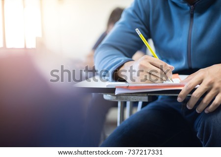 soft focus.high school or university student holding pencil writing on paper answer sheet.sitting on lecture chair taking final exam attending in examination room or classroom.student in uniform. Royalty-Free Stock Photo #737217331