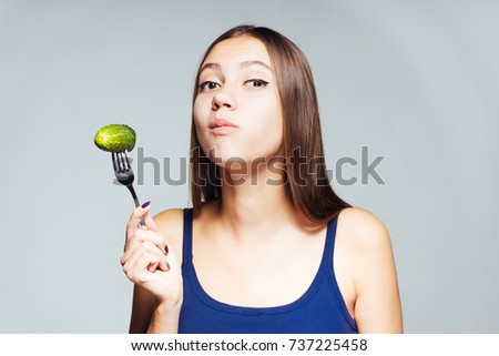 a young athletic girl watches her figure, eats a low-calorie cucumber
