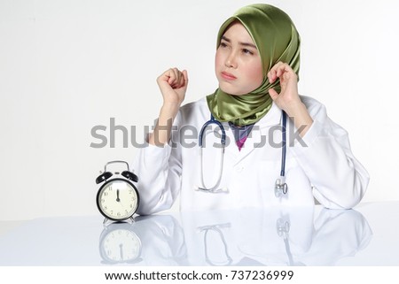 Portrait of stressed young pretty doctor and clock. Overworked concept.