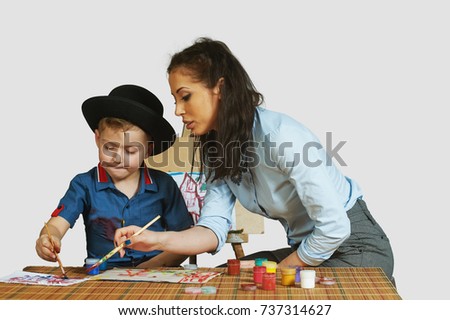 The woman helps the boy to develop the ability to painting . Young mother and son have been drawing . Isolated image