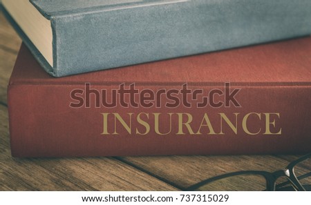 Learn insurance concept. Old law book on the topic of insurance on wood table.