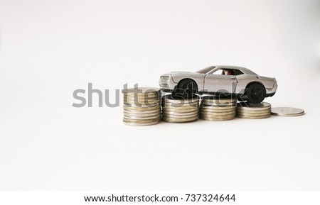 silver toy car on coins isolated on white background