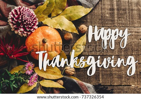 happy thanksgiving text sign on autumn pumpkin with leaves and walnuts and dahlias on stylish scarf top view, space for text. seasonal greetings, fall holidays. flat lay. harvest time. cozy mood