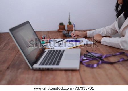 Business woman taking business notes  using laptop computer pen calculator paper clip paper work on wood table  . 
