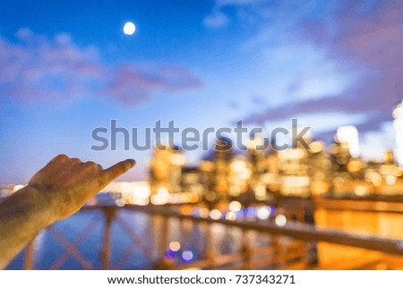 Blurred night city view with man hand pointing to buildings.