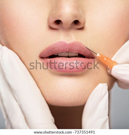 young woman gets injection of botox in her lips. Woman in beauty salon. plastic surgery clinic. Royalty-Free Stock Photo #737351491