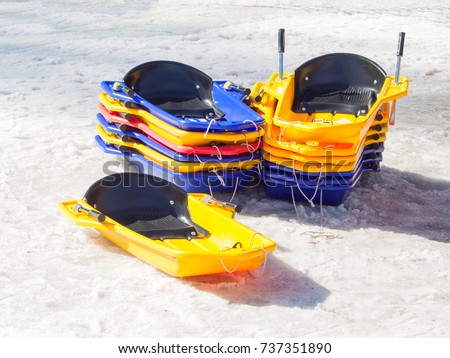 group of colorful toy bobsleigh stacked in the snow waiting for funny downhill
