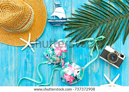 Summer Fashion woman big hat and accessories, vintage camera go to travel in the beach. Tropical sea.Unusual top view, blue background.  Summer Concept.
