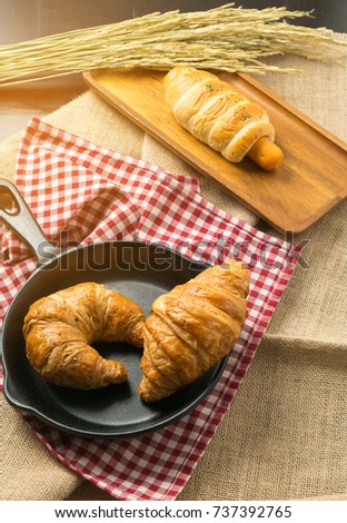 Tasty croissants with spikelets on table background.
