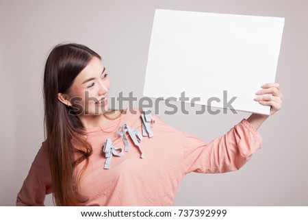 Young Asian woman with white blank sign on gray background