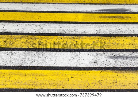 white and yellow stripes of a pedestrian crossing on an asphalt road. close-up photo
