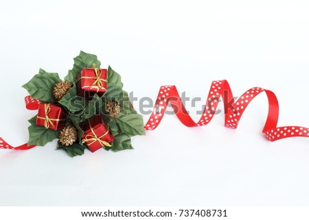 Decoration of crown-shaped parties on white background with red ribbon, green leaves and red gifts