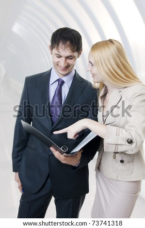 Two businessmen discussing in modern hall of office building and smiling. Business woman and man team.