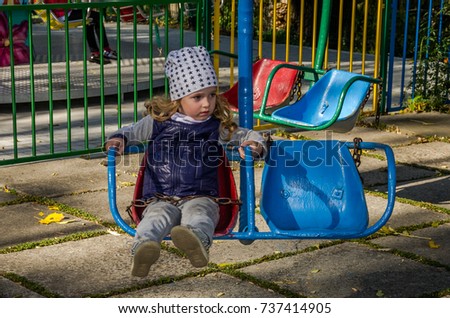 Little girl child swinging on a swing in an amusement park