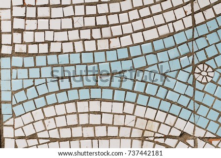 White and blue mosaic tiles with picture of sun or flower on the wall as background or texture
