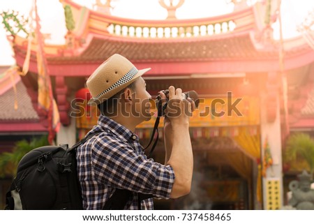Street photographer taking a picture of old shrine chinese temple in phuket old town with vintage camera ,side view.
Tourist sightseeing old town, travel concept.