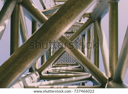 Complex ladder. Urban geometry, Street photography, Complex design. Modern art. Abstract art design.Steel beams. Industrial art. Industrial design. Blue sky background. Industrial geometry. Steel art,