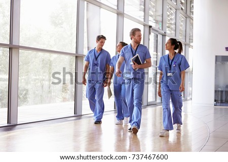 Four healthcare workers in scrubs walking in corridor Royalty-Free Stock Photo #737467600
