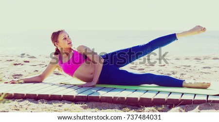 Woman 28-35 years old is practicing yoga on the beach near sea. Royalty-Free Stock Photo #737484031