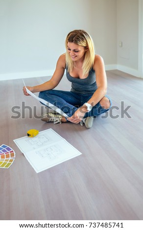 Girl looking house plans sitting on the floor