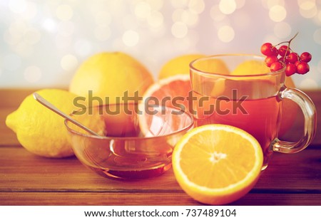 health, traditional medicine, folk remedy and ethnoscience concept - cup of tea with honey, lemon and rowanberry on wooden background Royalty-Free Stock Photo #737489104