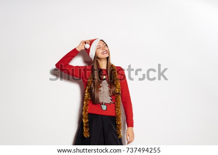 young happy girl celebrates New Year and Christmas, in a red cap and trendy sweater