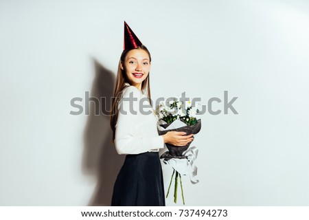 young beautiful girl celebrates something, in a red cap, holding a large bouquet of white flowers