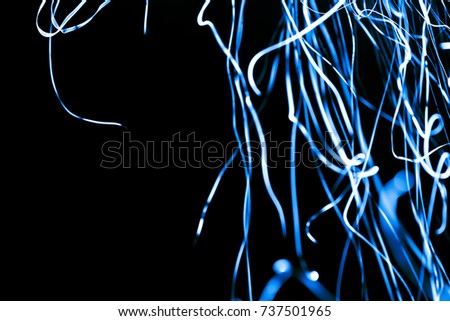 Abstract xmas blue transparent sparkles or glitter lights. Christmas festive black background. Defocused lines bokeh or particles. Template for design