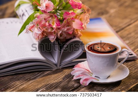 A cup of coffee, flowers and a magazine. Morning present. Fresh flowers and coffee. coffee with a smile and flowers