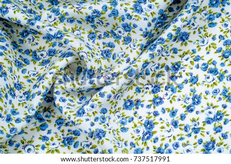 Background texture, pattern. thin cotton fabric with small blue flowers. Fabric has a white background with olive green flower stems and a mixture of tiny blue - aqua flowers. 