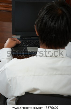 A close-up shot of a man working on his laptop