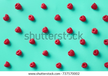 Colorful pattern of raspberries on blue background. From top view