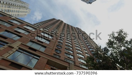 Straight up vertical view establishing photo of generic office or luxury real estate apartment building  Skyscraper tower towards blue sky with clouds