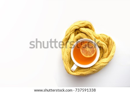 Mug of hot tea in a scarf in the form of heart on a white background