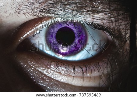 Eye close-up with a purple pupil on a halloween horror